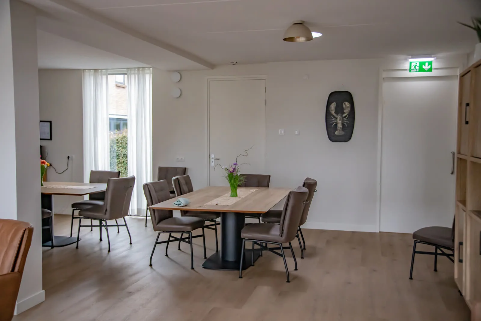 De gezamenlijke eetkamer met gedekte tafels en verse bloemen