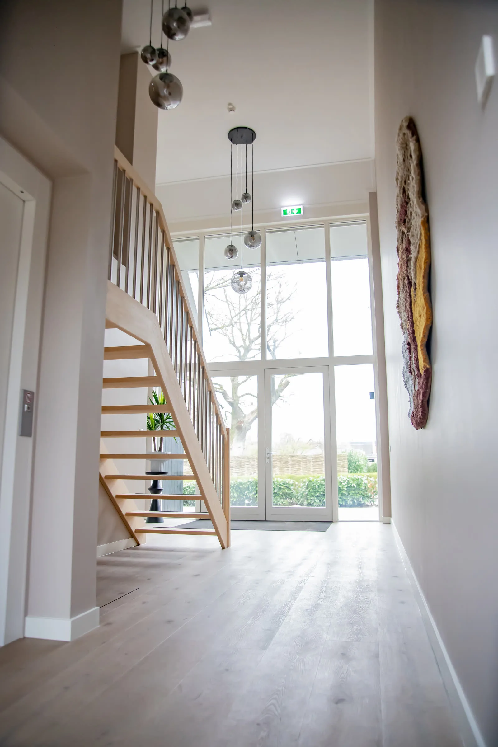 De lichte entree van Zorgvilla Nova met houten trap en hoge glazen pui