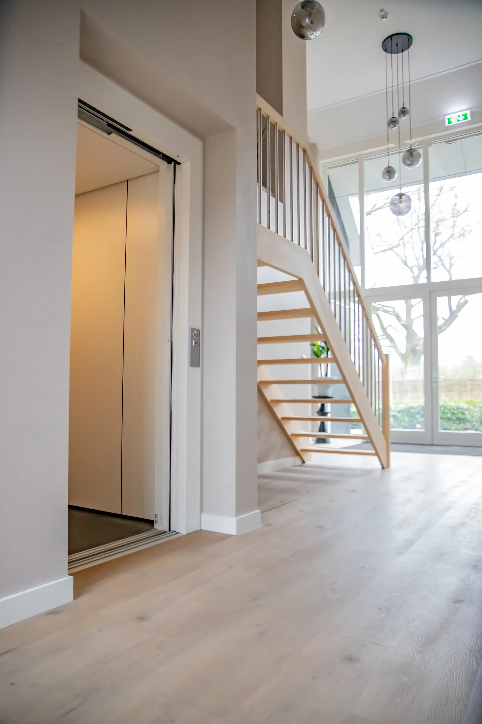 De centrale hal met lift en houten trap