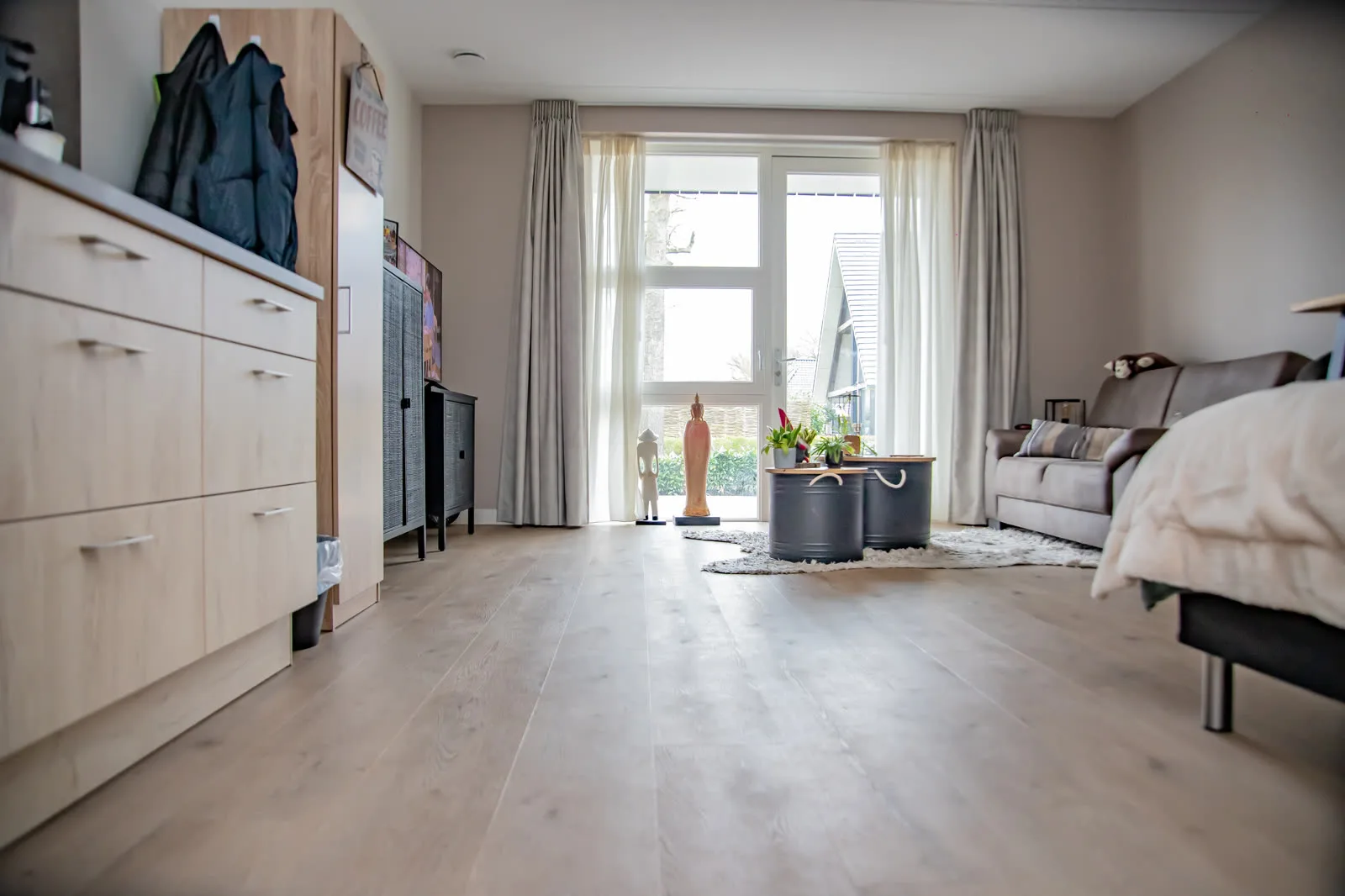 Een ruime lichte studio met zithoek, keukenblok en openslaande tuindeuren