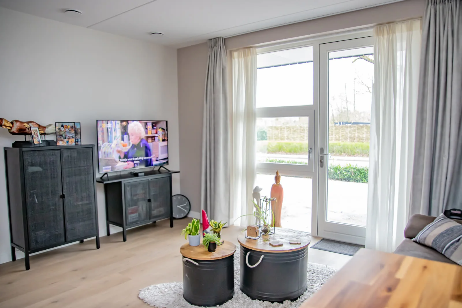 Woonhoek van een bewoonde studio met tv en tuindeuren